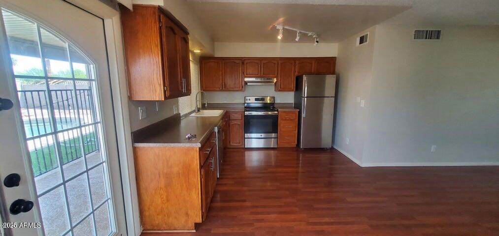 824 West Fordham Drive Tempe, AZ 85283 - Photo 3 of 20 a kitchen with stainless steel appliances granite countertop a refrigerator a sink dishwasher a stove and a dining table with wooden floor