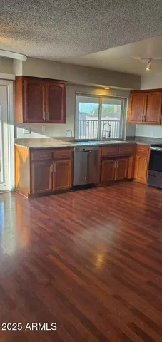 a view of kitchen with stainless steel appliances wooden floor and a large window