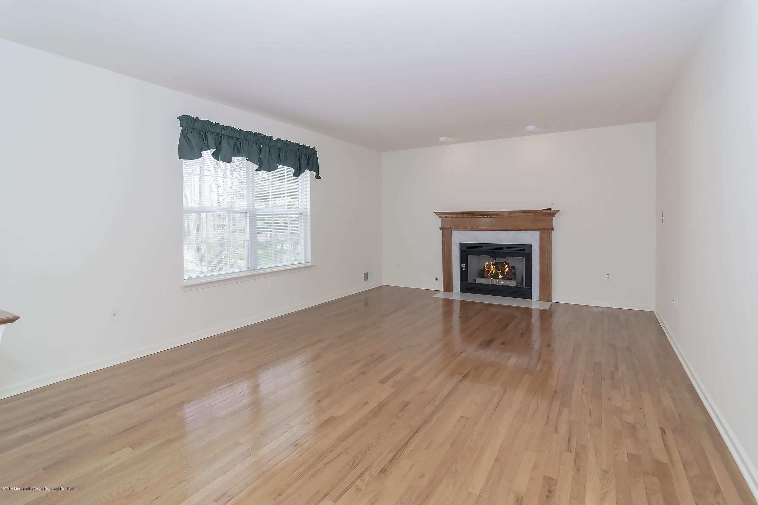 403 Meadowood Road Jackson, NJ 08527 - Photo 7 of 46 an empty room with wooden floor and a window