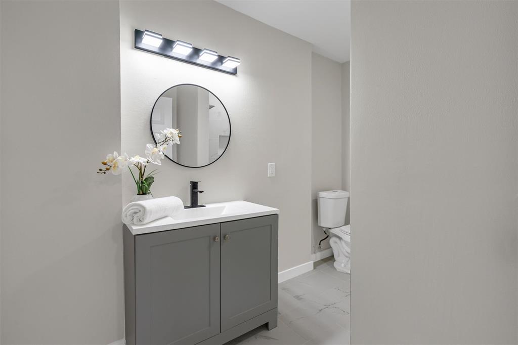 4815 Kelman Street Dallas, TX 75214 - Photo 28 of 37 Bathroom vanity featuring a matte black faucet, white countertop, and gray shaker-style cabinetry