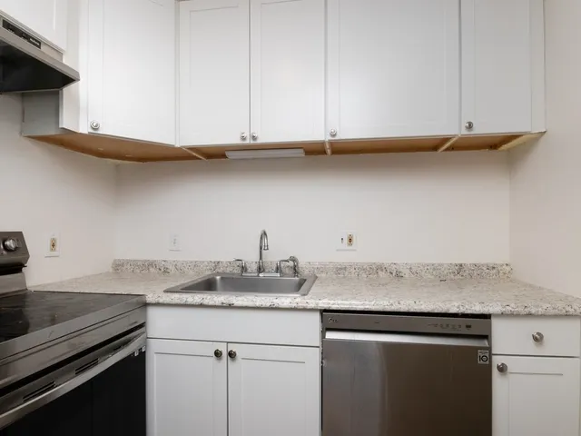 a kitchen with granite countertop white cabinets and a stove