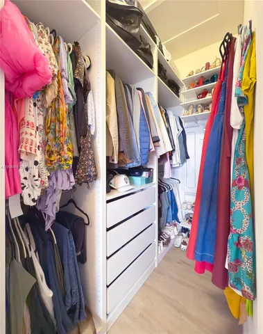 a view of walk in closet with clothes and shoes