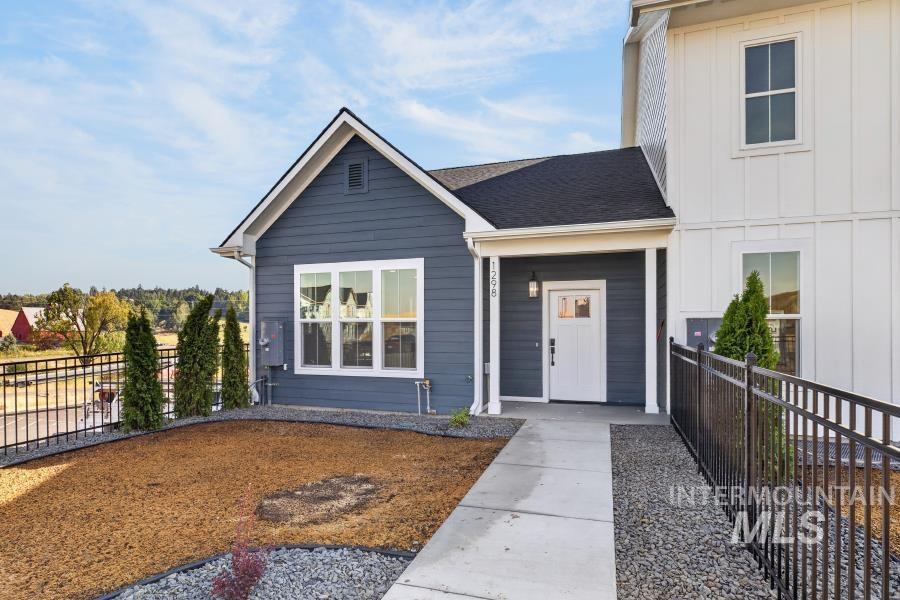 Contemporary exterior with dark blue siding and white board-and-batten accents, featuring a covered entry, concrete walkway, and black metal fencing