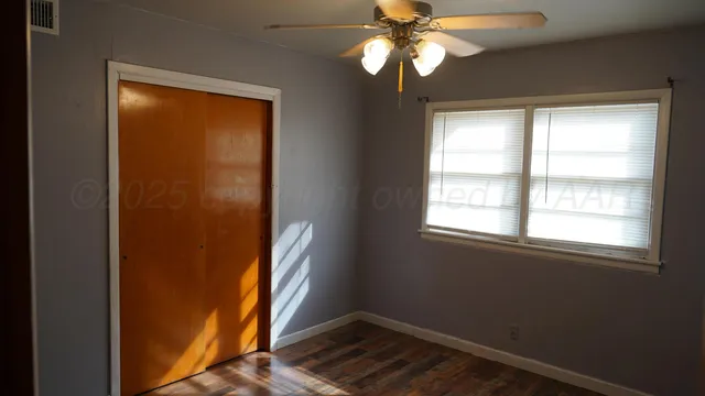 an empty room with windows and fan