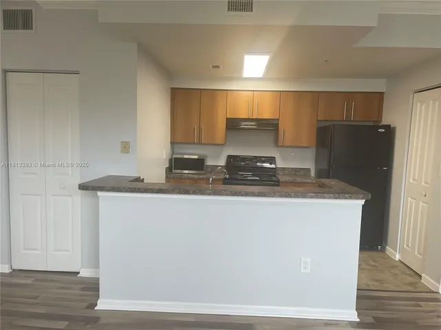 a kitchen with kitchen island granite countertop cabinets and refrigerator