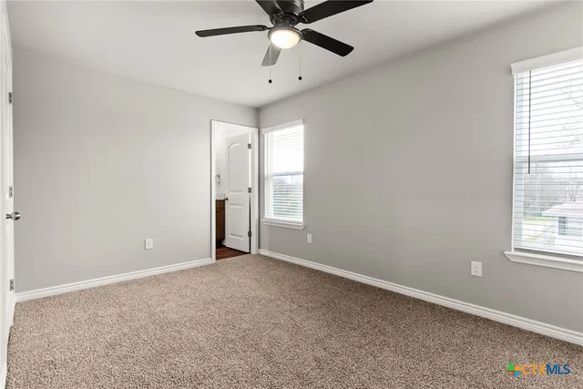 an empty room with windows and fan