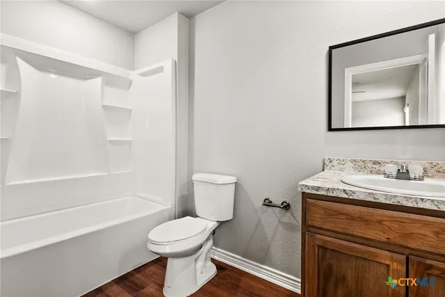 a bathroom with a granite countertop toilet sink and mirror