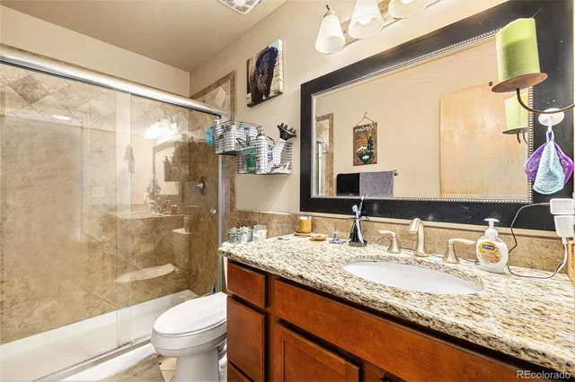 a bathroom with a granite countertop sink toilet mirror and shower