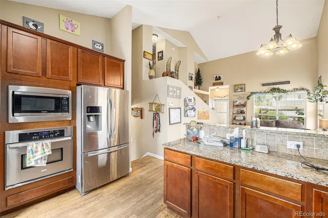 a kitchen with stainless steel appliances granite countertop a refrigerator a oven and white cabinets with wooden floors
