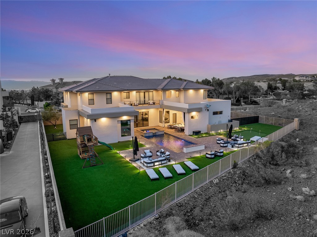 5 Crystal Tree Pass Henderson, NV 89052 - Photo 60 of 67 An aerial view showcases a contemporary home with a shimmering pool and spacious entertainment area at dusk.