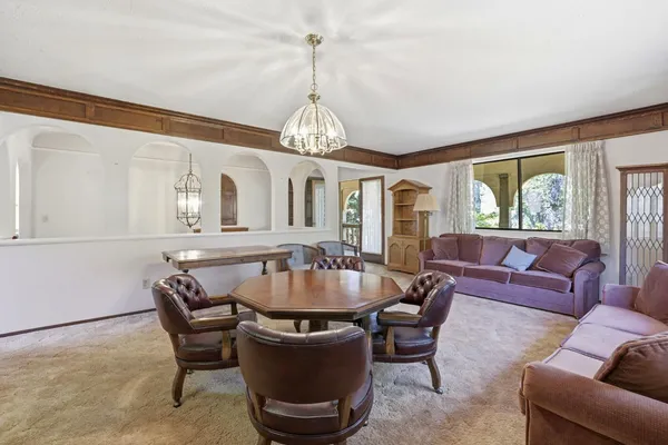 a living room with furniture a chandelier and a dining table