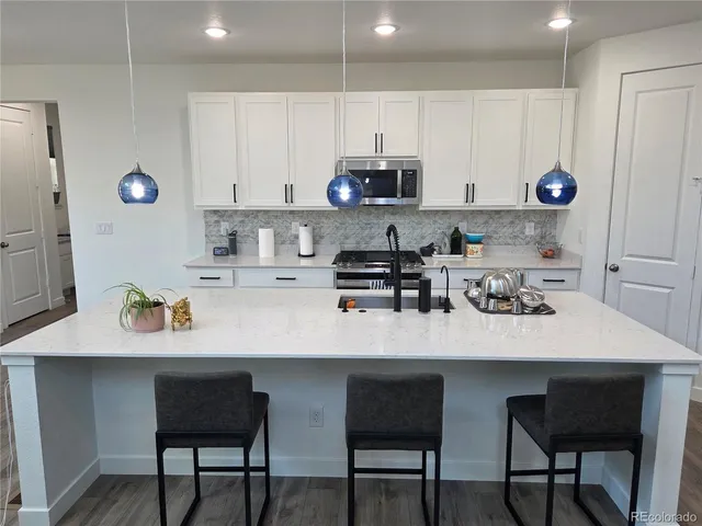 a kitchen with stainless steel appliances a white table and chairs in it