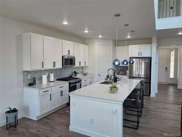 a kitchen with a stove a sink and a refrigerator with wooden floor