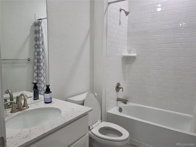 a bathroom with a granite countertop sink toilet a mirror and shower