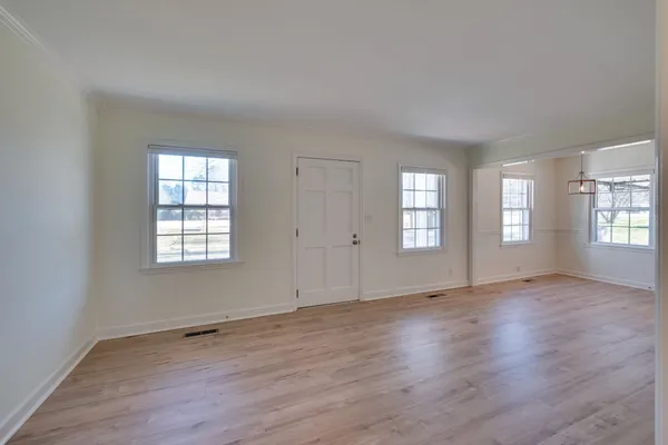 a view of an empty room with window and wooden floor