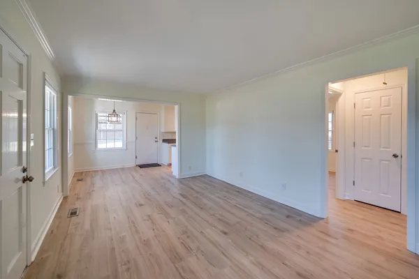 a view of an empty room with a window and wooden floor
