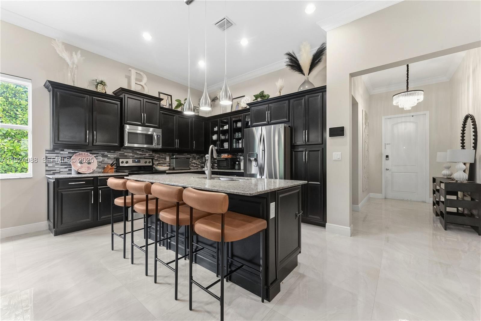 14929 Southwest 176th Terrace Miami, FL 33187 - Photo 9 of 38 a kitchen with stainless steel appliances kitchen island granite countertop a table chairs sink and cabinets
