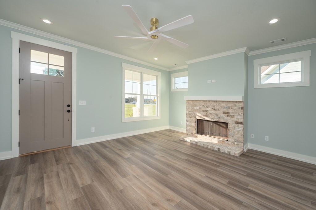 1190 Lee Road Phenix City, AL 36870 - Photo 10 of 52 an empty room with windows a fireplace a ceiling fan and wooden floor