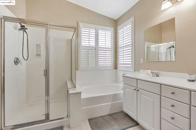 a bathroom with a double vanity sink a large mirror and a bathtub