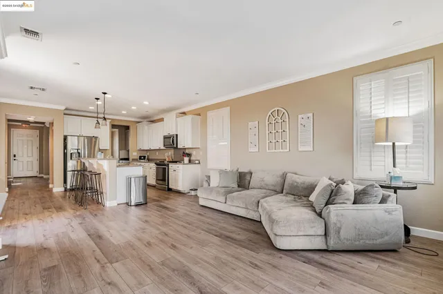 a living room with furniture and kitchen view with wooden floor