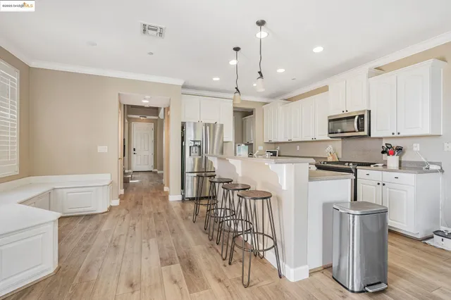 a kitchen with stainless steel appliances granite countertop a table chairs refrigerator and microwave