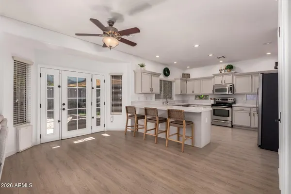 a open kitchen with stainless steel appliances granite countertop a stove top oven a refrigerator a dining table and chairs with wooden floor