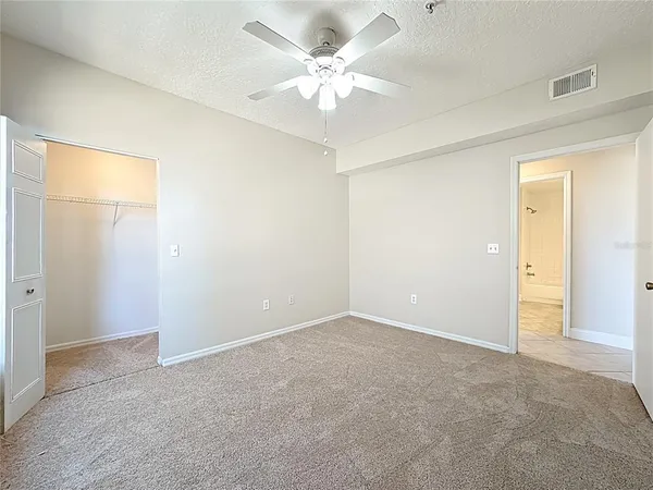 an empty room with windows and ceiling fan