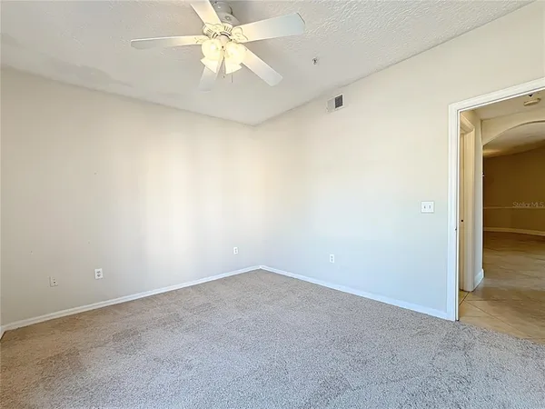 an empty room with a chandelier fan and windows