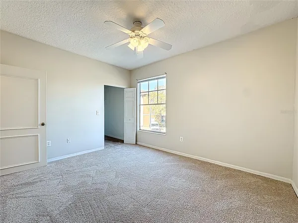 an empty room with windows and chandelier fan