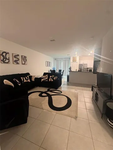 a living room with furniture a flat screen tv and kitchen view