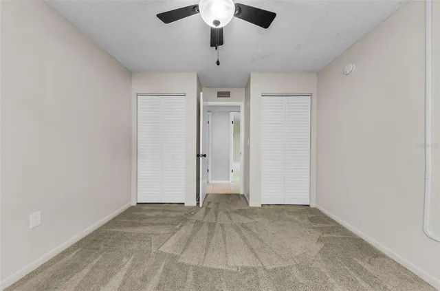 an empty room with a window and a fan