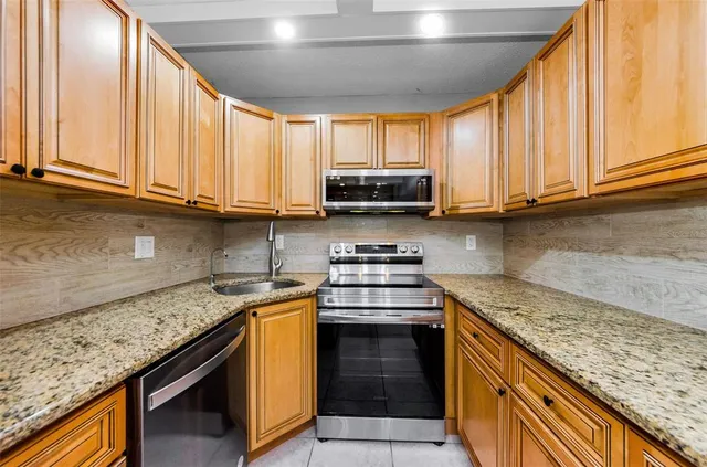 a kitchen with stainless steel appliances granite countertop a stove a sink and a microwave