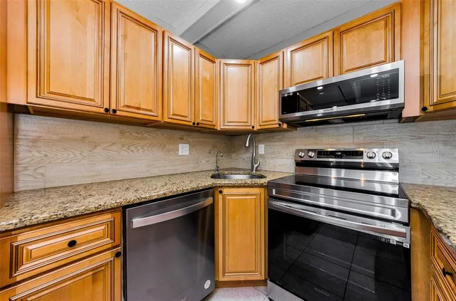 a kitchen with stainless steel appliances granite countertop a sink stove and microwave