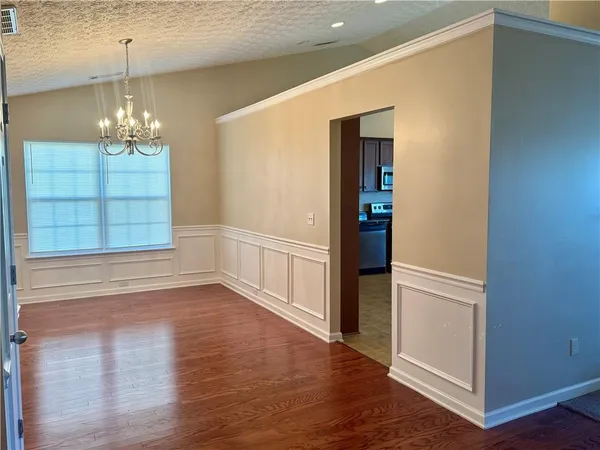 an empty room with wooden floor chandelier and windows