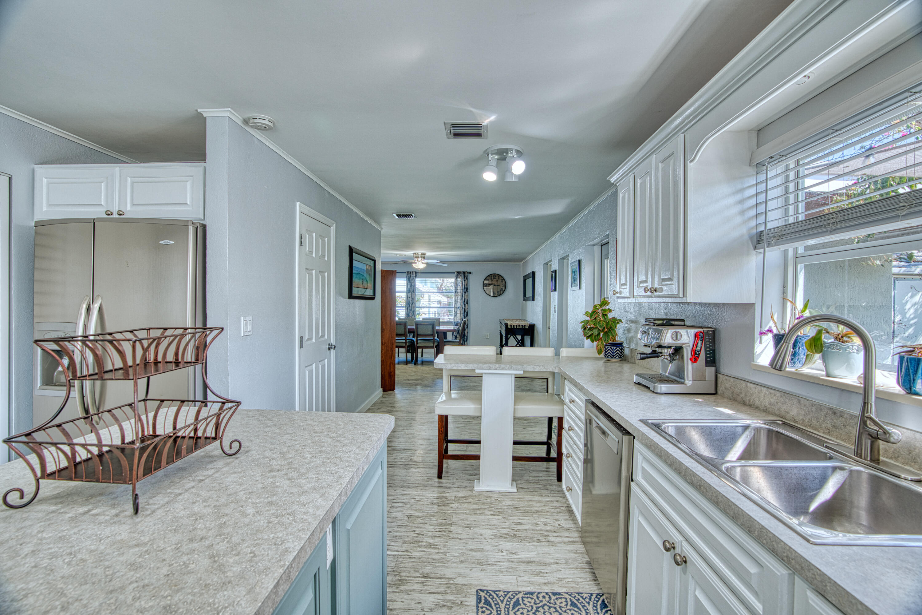 136 1st Road Key Largo, FL 33037 - Photo 22 of 45 a kitchen with stainless steel appliances granite countertop a sink dishwasher a stove a refrigerator a dining table and chairs with wooden floor