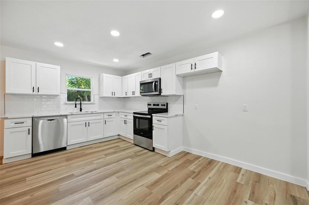 4413 Quails Lane Fort Worth, TX 76119 - Photo 8 of 20 a kitchen with granite countertop white cabinets and stainless steel appliances