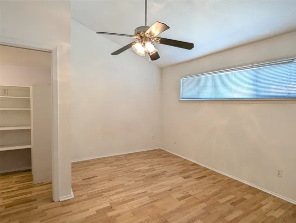 a view of a room with wooden floor and a ceiling fan