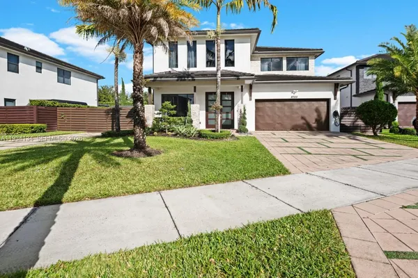 a front view of a house with a yard and potted plants