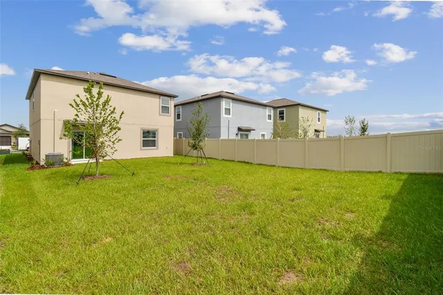 a view of a big house with a big yard and large tree