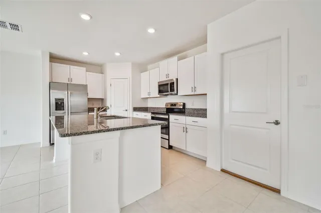 a kitchen with granite countertop white cabinets and stainless steel appliances