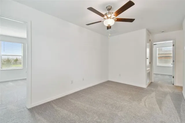 an empty room with a ceiling fan and a window