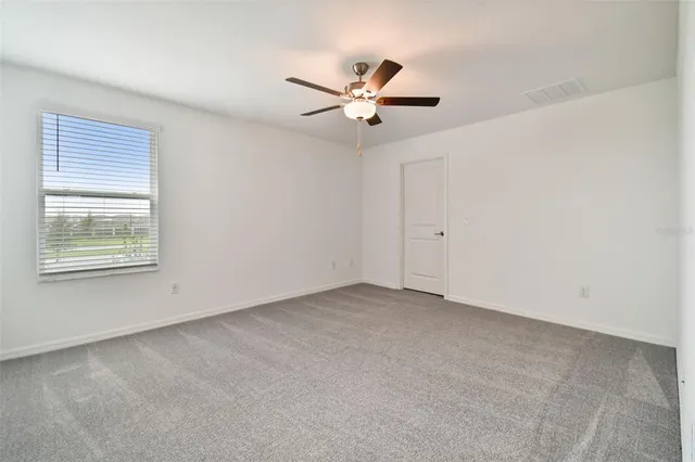 an empty room with windows and fan