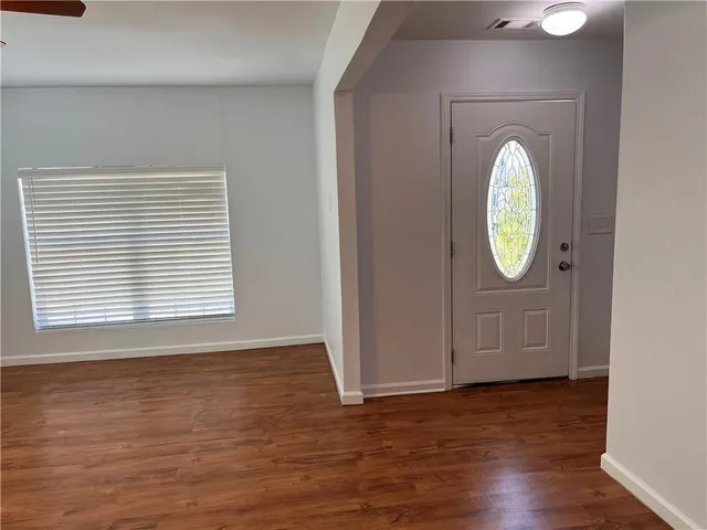 an empty room with wooden floor mirror and windows