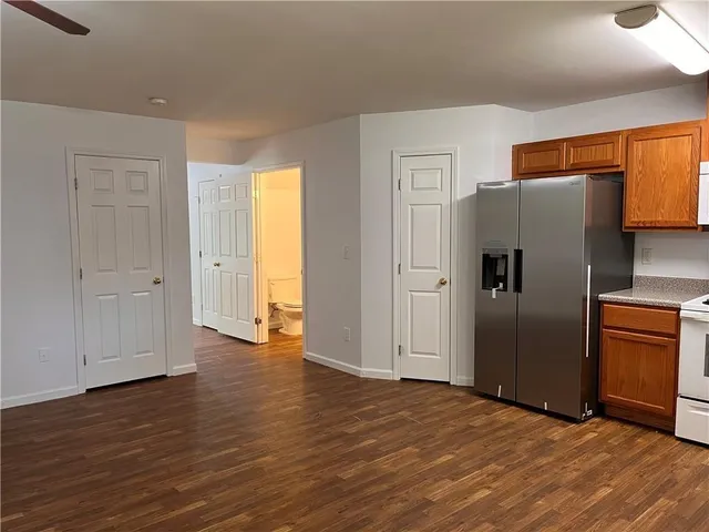 a view of an empty room with wooden floor and a refrigerator