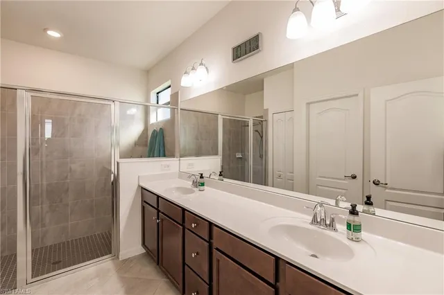 a bathroom with a double vanity sink mirror and shower