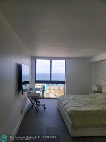 a bedroom with a bed table chair and a window