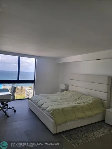 a bedroom with a bed and large windows