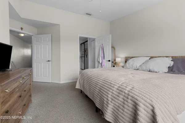 a spacious bedroom with a bed and a flat screen tv