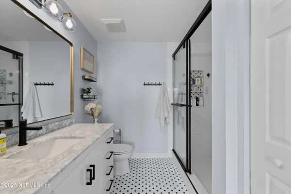 a bathroom with a granite countertop sink a toilet and shower