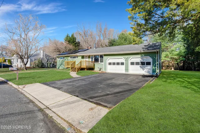 a white house that has a small yard and couches chairs with wooden fence